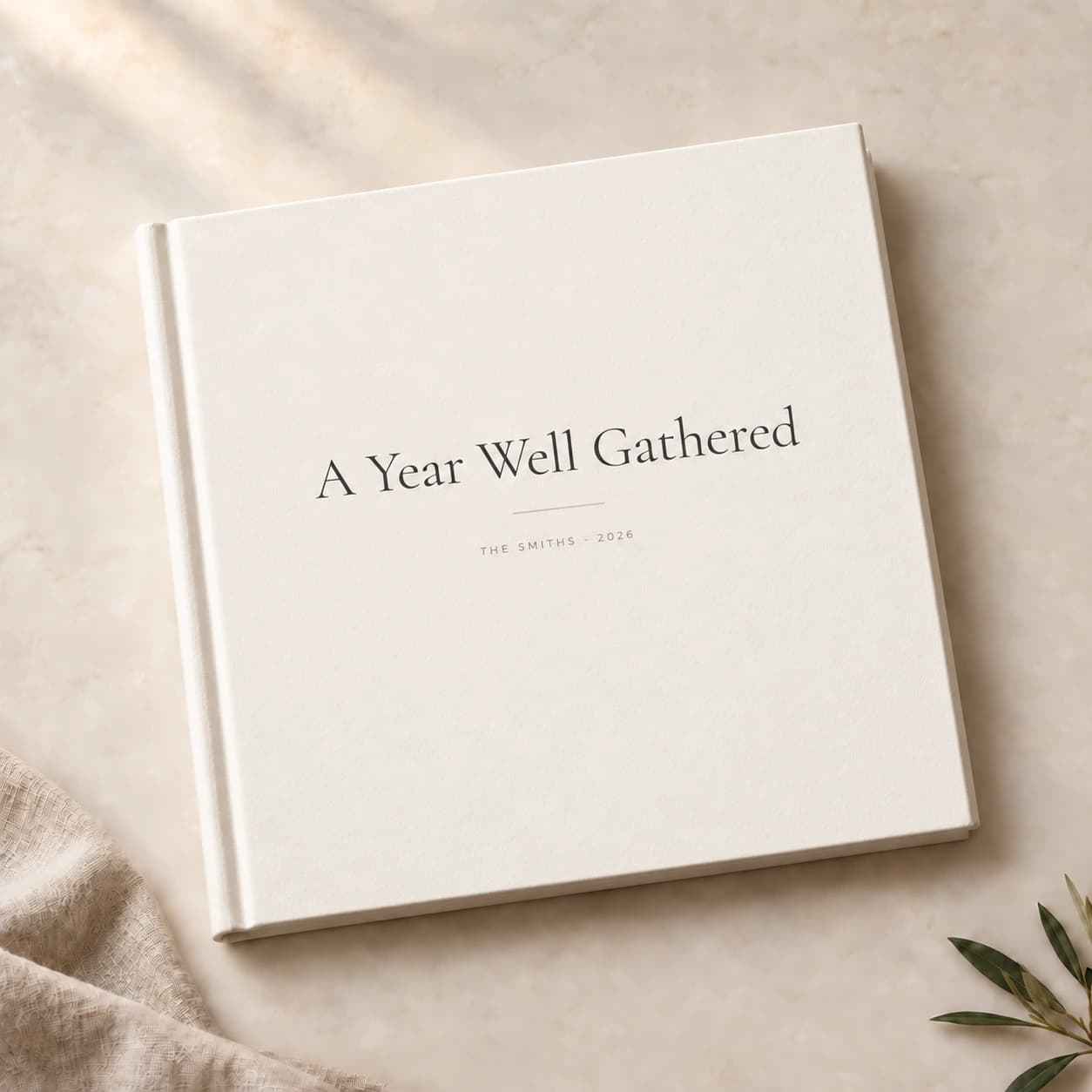 A Year Well Gathered, personalized THE SMITHS - 2026, on an ivory matte yearbook beside linen fabric and olive leaves
